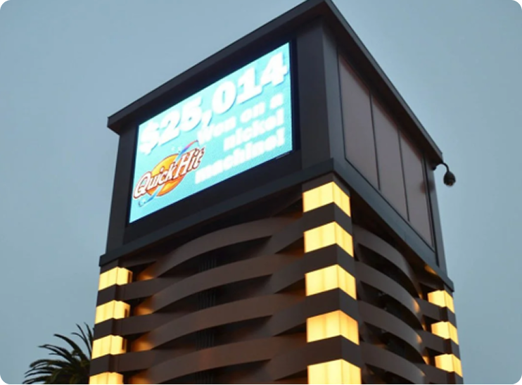 A digital sign atop a building displays an advertisement for "Quick Hit" with a jackpot of "$25,014 Won on a nickel machine!".