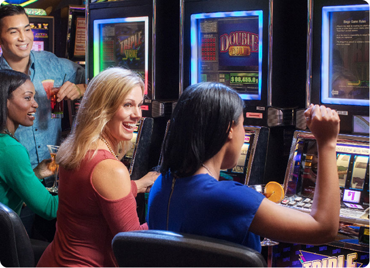 A diverse group of friends smiling and playing slot machines in a lively casino, enjoying drinks and entertainment.